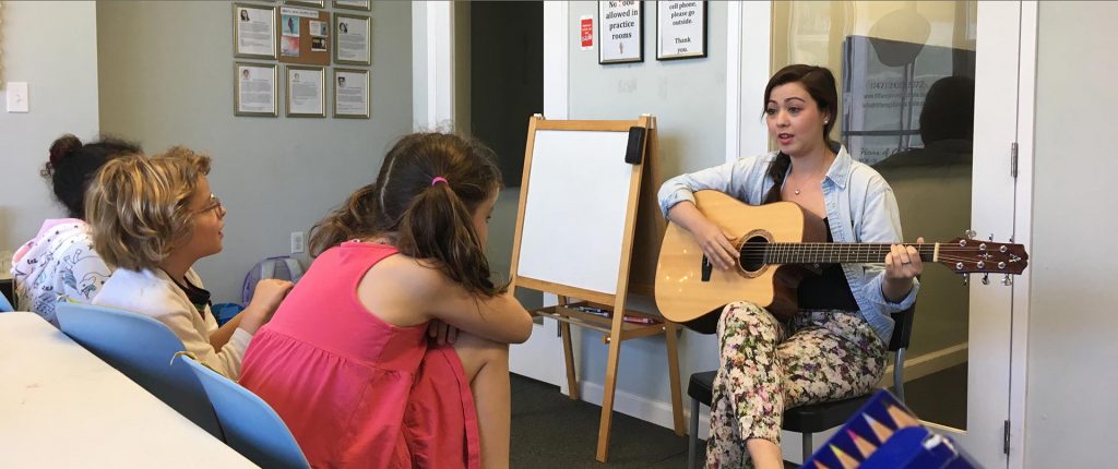 Child and adult learning guitar in lesson setting